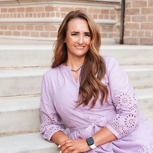 Woman in lavender dress sitting outdoors.